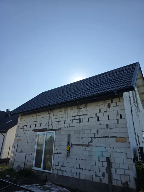 Naujai uždengtas stogo šlaitas virš mūrinės sienos
